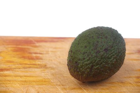 whole avocado black skin variety over white isolated on boardの写真素材