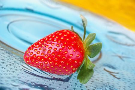 single strawberry blue glass plate yellow background の写真素材