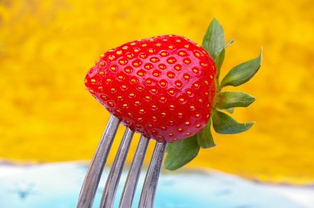 a single strawberry on a silver forkの写真素材