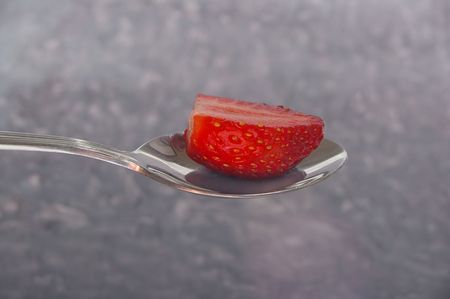 single red strawberry half on silver spoonの写真素材
