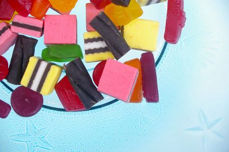 soft colored jelly lollies and licorice on blue glass plateのeditorial素材