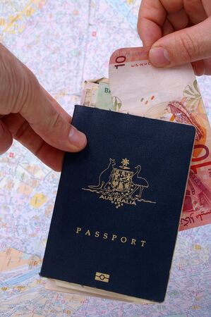 australian passport and holder on top of paris map with cash exchanging handsの写真素材