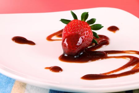 Single strawberry with brown sryup either chocolate vinegar or sauceの写真素材