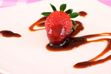 Single strawberry with brown sryup either chocolate vinegar or sauceの写真素材