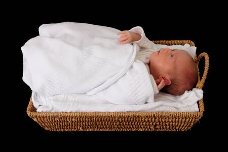 baby in wicker moses basket isolated over blackの写真素材