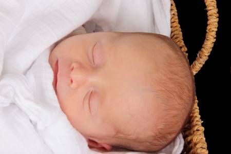 baby in wicker moses basket isolated over blackの写真素材