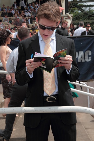 BRISBANE, AUSTRALIA  NOV 01 : Young man studies form guide of the big race at Eagle Farm Racourse Melbourne Cup race day November 01, 2011 in Brisbane, Australia のeditorial素材