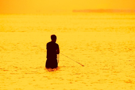silhouette of fisherman using net during sunrise brisbane queensland australiaの写真素材