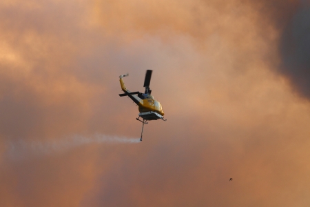 NINGI, AUSTRALIA - NOVEMBER 9   Waterbomber helicopter with full load heading to fire front into clouds of smoke November 9, 2013 in Ningi, Australiaのeditorial素材