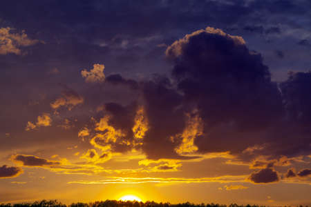 Beautiful sunset behind the forest. View of dark clouds and the vivid color of the sky.の写真素材