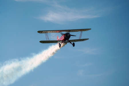 Biplane airplane flies in a picturesque cloudy sky. Old school aircraft aviation