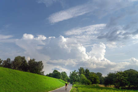 Beautiful view of the rural landscape with a cyclist on the road.の写真素材