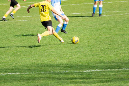 The young footballer kicks the ball hard towards the opponentの写真素材