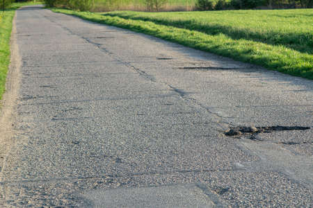 Destroyed asphalt road surface. Cracks and holes in the road are dangerous for the drivers.の写真素材