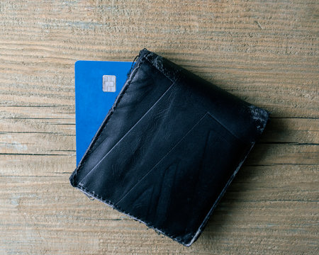 Old used purse and blue payment card on a wooden background.の写真素材
