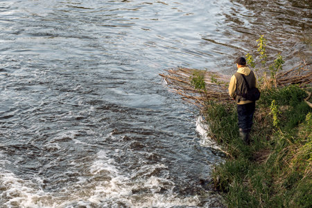 Man fishing with a rod on the river bank on a sunny day.