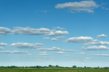 A horizontal photo of beautiful clouds over a farmland in the summer timeの写真素材