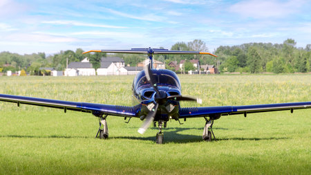 Horizontal photo of a small airplane standing on the airport grass with its engine runningの写真素材