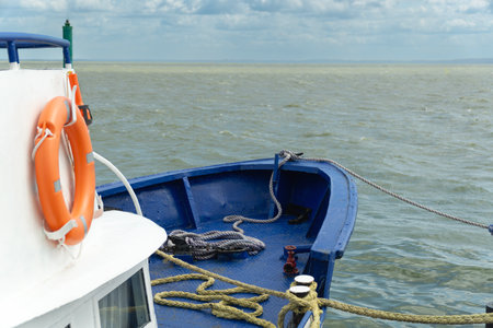 Horizontal shot of a rough sea and the front of a ship with a lifebuoy.の写真素材