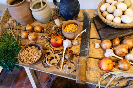 A horizontal photo of a wooden table with vegetables and various things spread out on it