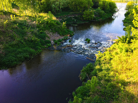 A horizontal photo of a small river flowing into a large river in Mayの写真素材