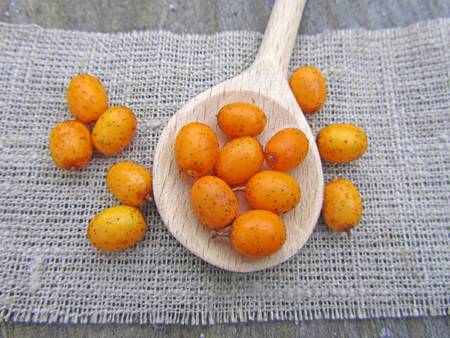 ripe sea buckthorn in wooden spoon, close-up