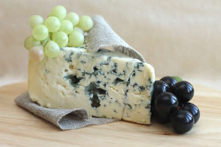 Slice of blue cheese with grapes on wooden background, close-upの写真素材
