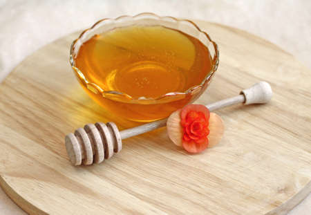 Bowl of honey with wooden drizzler, close-upの写真素材
