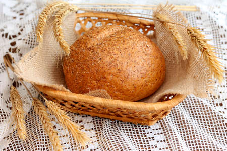 Tasty homemade bread in basket with spikelets, close-up