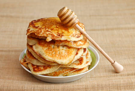 pancakes with honey and wooden dipper on canvas background, close-up