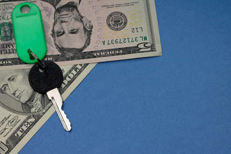 Concept of rental housing. Key with dollars on blue backdropの写真素材
