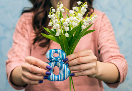 Gift on March 8. Girl holding lily of valley, close-up