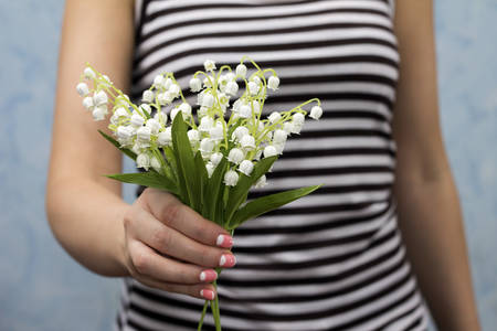 Slim girl dressed in frock posing with lily of valleyの写真素材