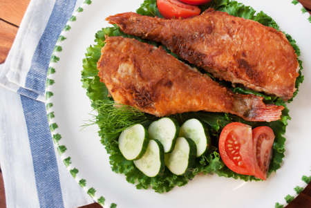 Top view of cooked sea bass on plate with vegetablesの写真素材