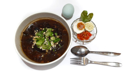 Black meat soup Rawon in a white bowl served with leek, bean sprouts, salted egg, lime, chili sambal, crackers. Popular Indonesian food from Ponorogo, East Javaの写真素材