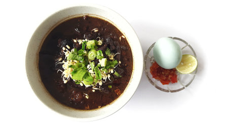 Black meat soup Rawon in a white bowl served with leek, bean sprouts, salted egg, lime, chili sambal, crackers. Popular Indonesian food from Ponorogo, East Javaの写真素材