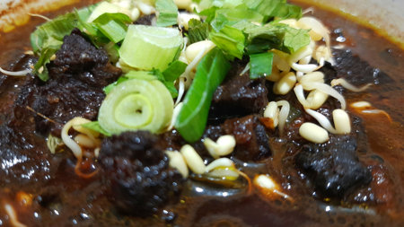 Black meat soup Rawon with leeks and bean sprouts in a white bowl isolated on white backgroundの写真素材