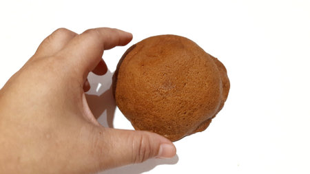 Hand holding a Coffee Bun isolated on white background.
