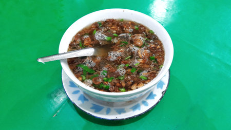 Beef soup or sop daging with rice noodles and potato croquettes. Indonesian clear soup on green...