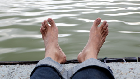 the view of the foot of a person who is exhausted on the lake at sunsetの写真素材