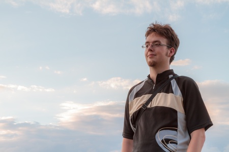 Young caucasian man looking into the distance Male student with glasses, beard and a biking outfit,...