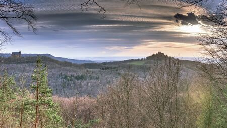 Sunset in the Hills of Franconia, Germany on evening to early April. Barren trees in the forrest. Panoramic format. Rural Countryside. Mountain Chapel and Castleのeditorial素材