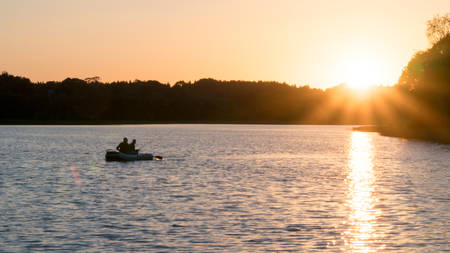 Beautiful sunset on the lake, fishermen on the boat.の写真素材