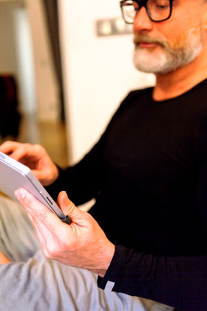 Modern middle-aged man with glasses enjoying a quiet moment His comfortably at home with a tablet