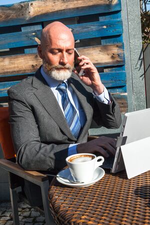 Middle-aged man, handsome and elegant working outside the office in a relaxed and sunny atmosphereの写真素材