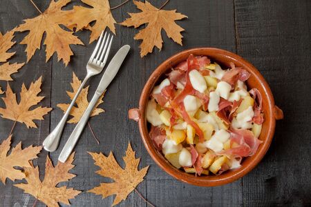 Hot Mediterranean meal. Image linked to a traditional Mediterranean food with ham, cheese and baked potatoes decorated with autumn leaves and cutleryの写真素材
