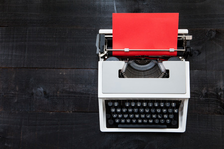 Typewriter and red paper. The image above dealer to retro typewriter on a dark wood background with...
