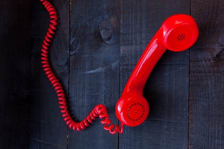 The retro red telephone. The image above dealer in vintage red phone on a dark wood background Conceptualizing communication or lack thereofの写真素材