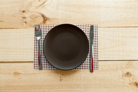 The image shows a wooden table with a plate and cutlery as seasonal rustic decor as backgroundの写真素材