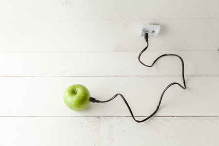 The picture shows an apple connected to an ethernet cable conceptualizing the internet of things and wearablesの写真素材